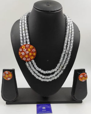 Jewelry set with a necklace and earrings on a black stand against a white background